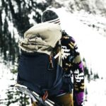 A hiker wearing a colorful jacket explores a snowy mountain in Glacier, Canada.
